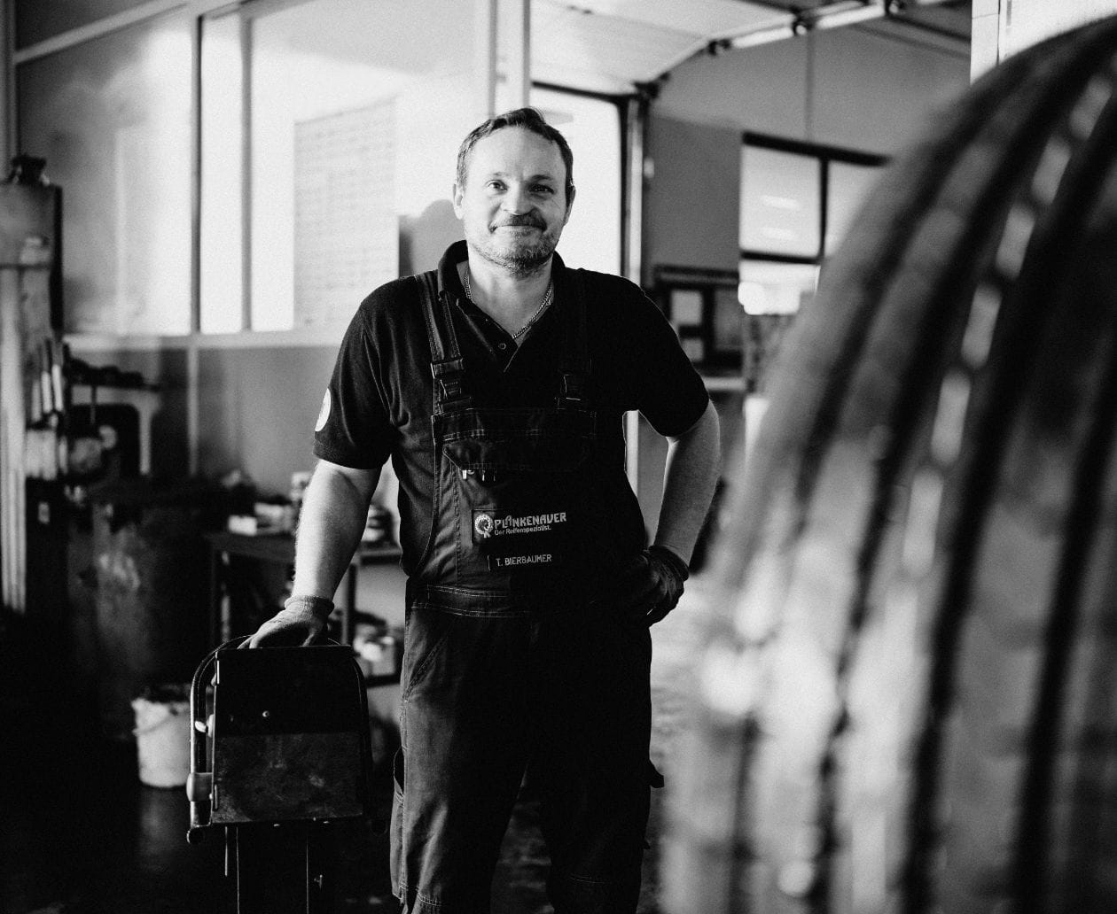 Thomas Bierbaumer in Arbeitskleidung in der Werkstatt mit Reifen.