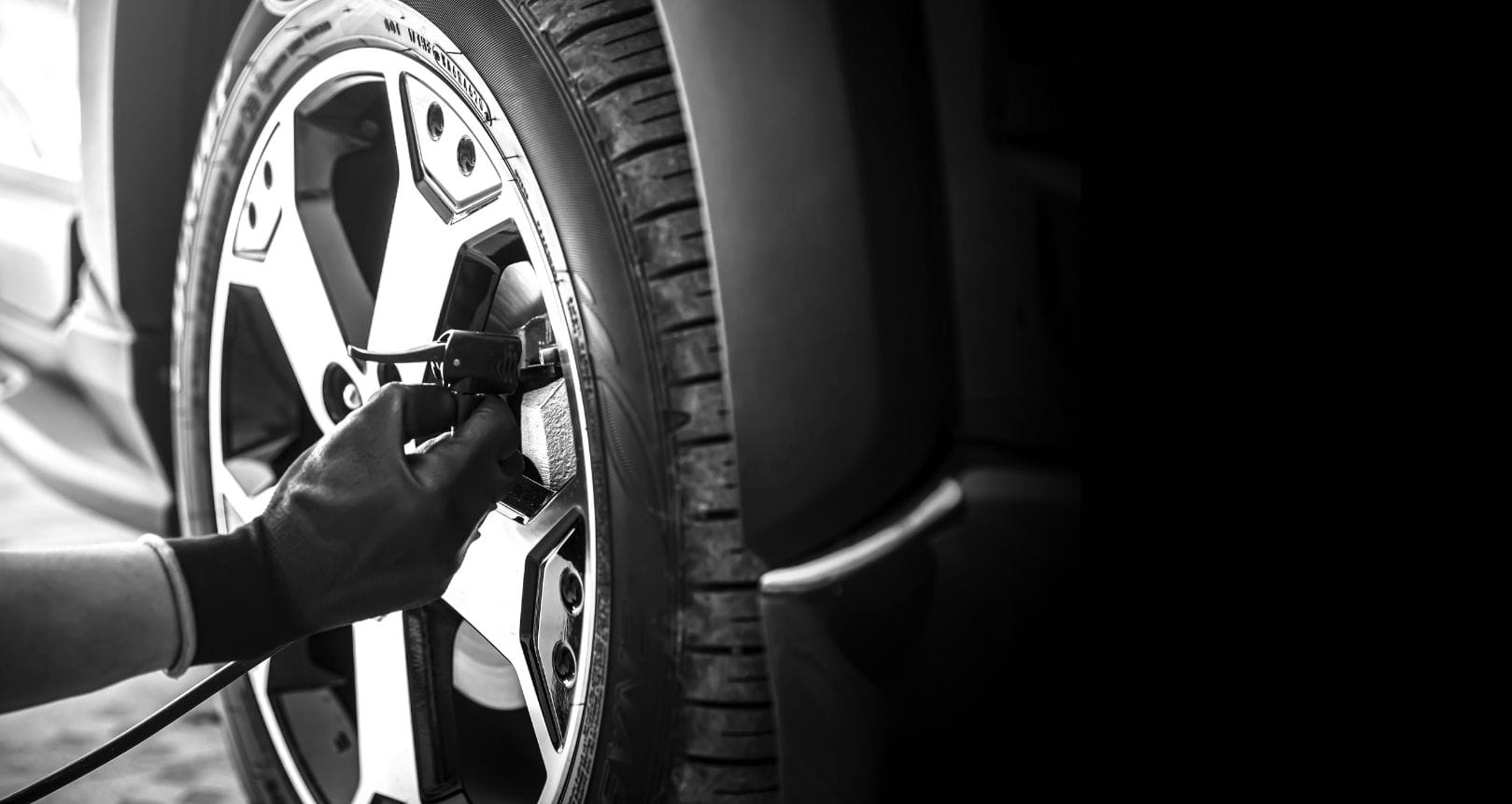 Ein Mitarbeiter prüft den Reifendruck mit einem digitalen Messgerät.