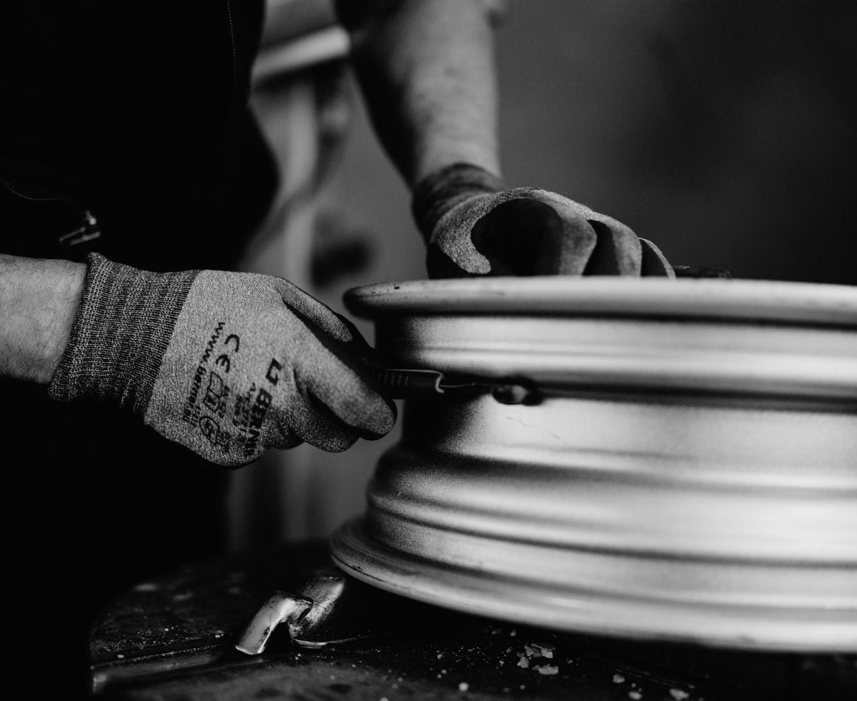 Nahaufnahme einer Hand mit Werkzeug, die an einer Felge von der Seite arbeitet.