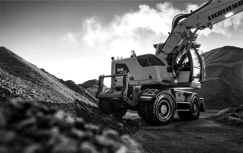 Baumaschine auf Schotterplatz mit riesigem Reifenprofil – Einsatzbereich Erdbewegung.