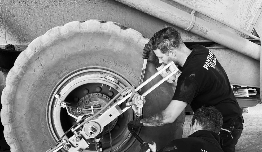 Reifenmonteur arbeitet in Werkstattumgebung an einem ausgebauten Lkw-Rad.