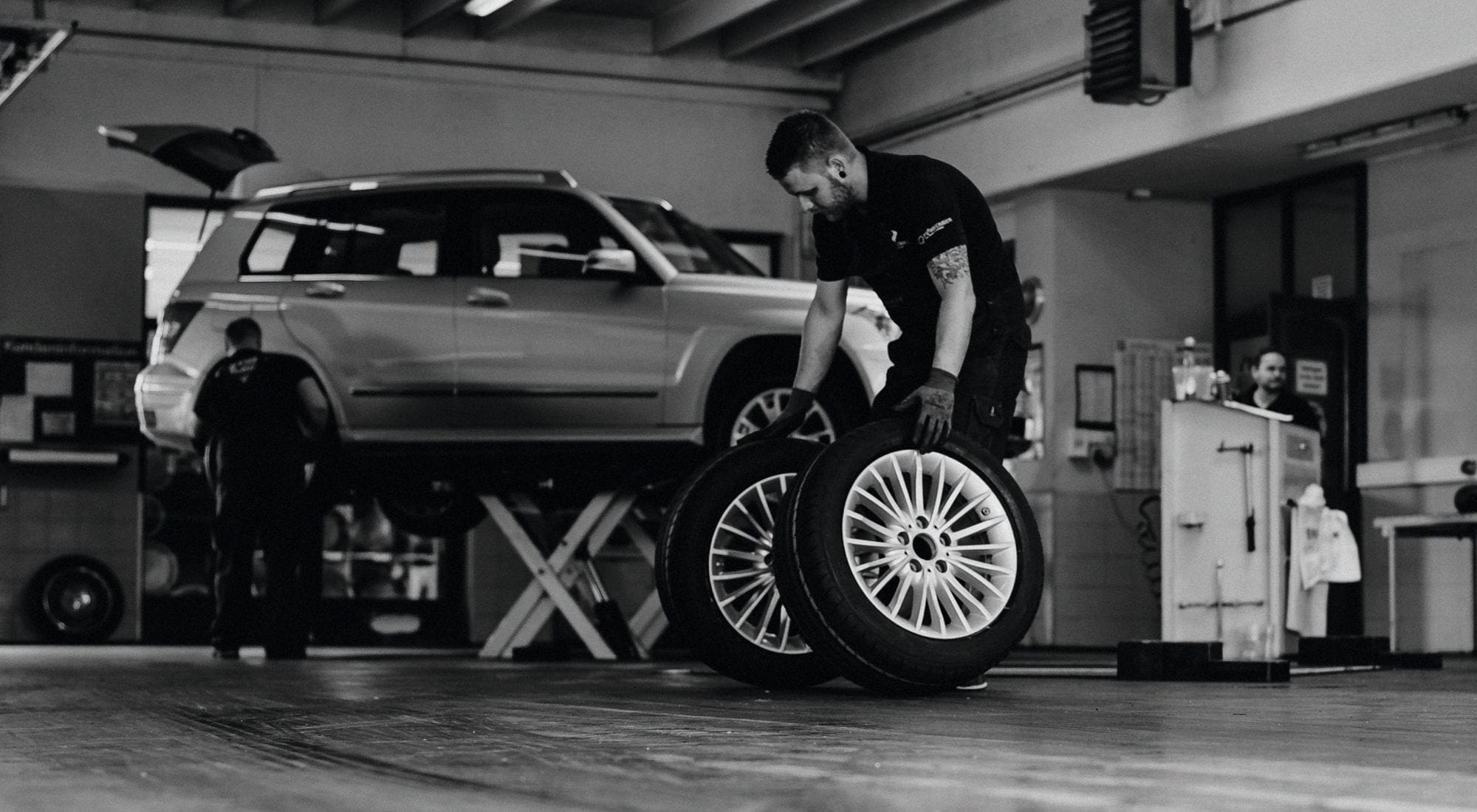Mechaniker montiert Reifen an einem Auto auf der Hebebühne.