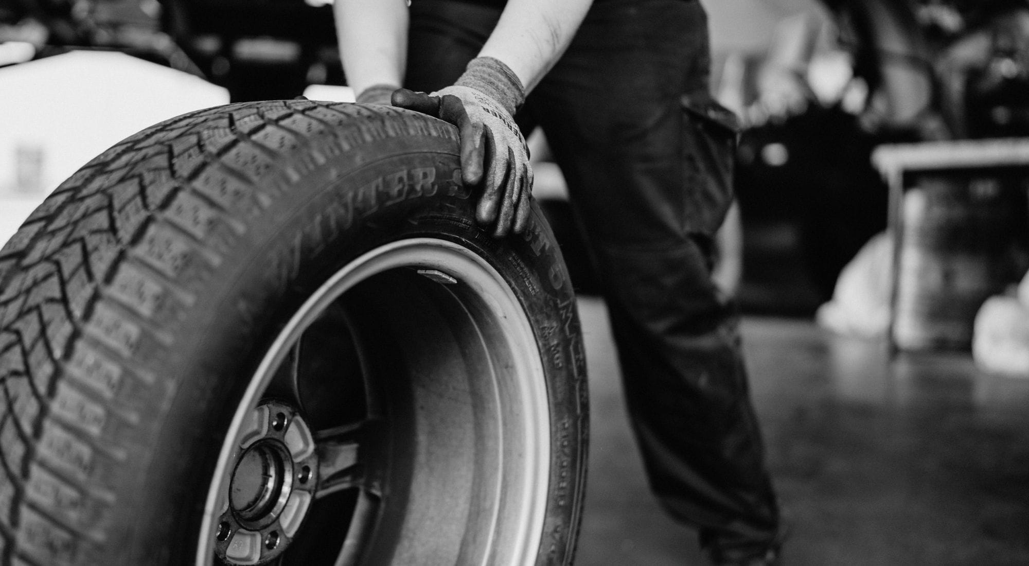 Ein Mitarbeiter rollt einen Reifen mit ausgestrecktem Arm