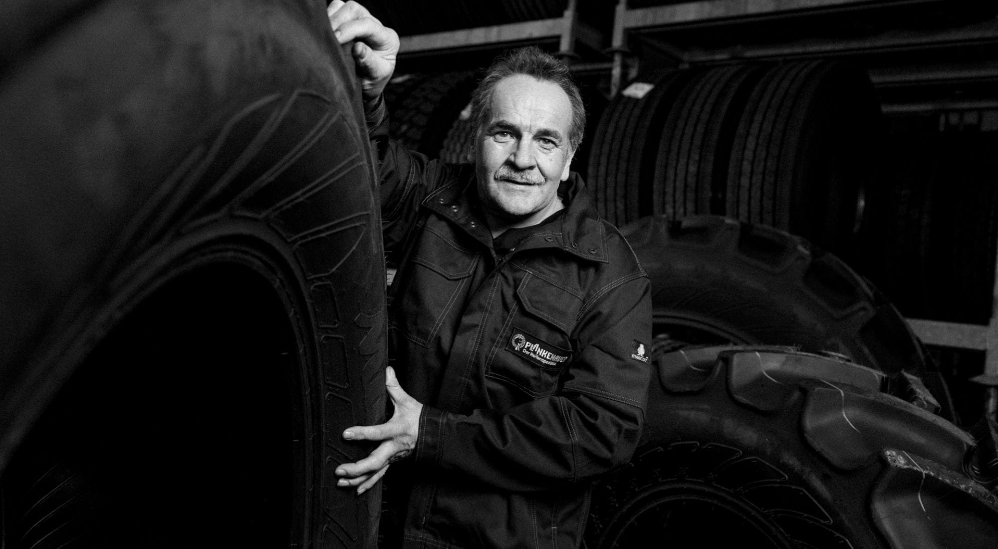 Großer Reifen aufrecht stehend, ein Mitarbeiter im Hintergrund bei der Arbeit.