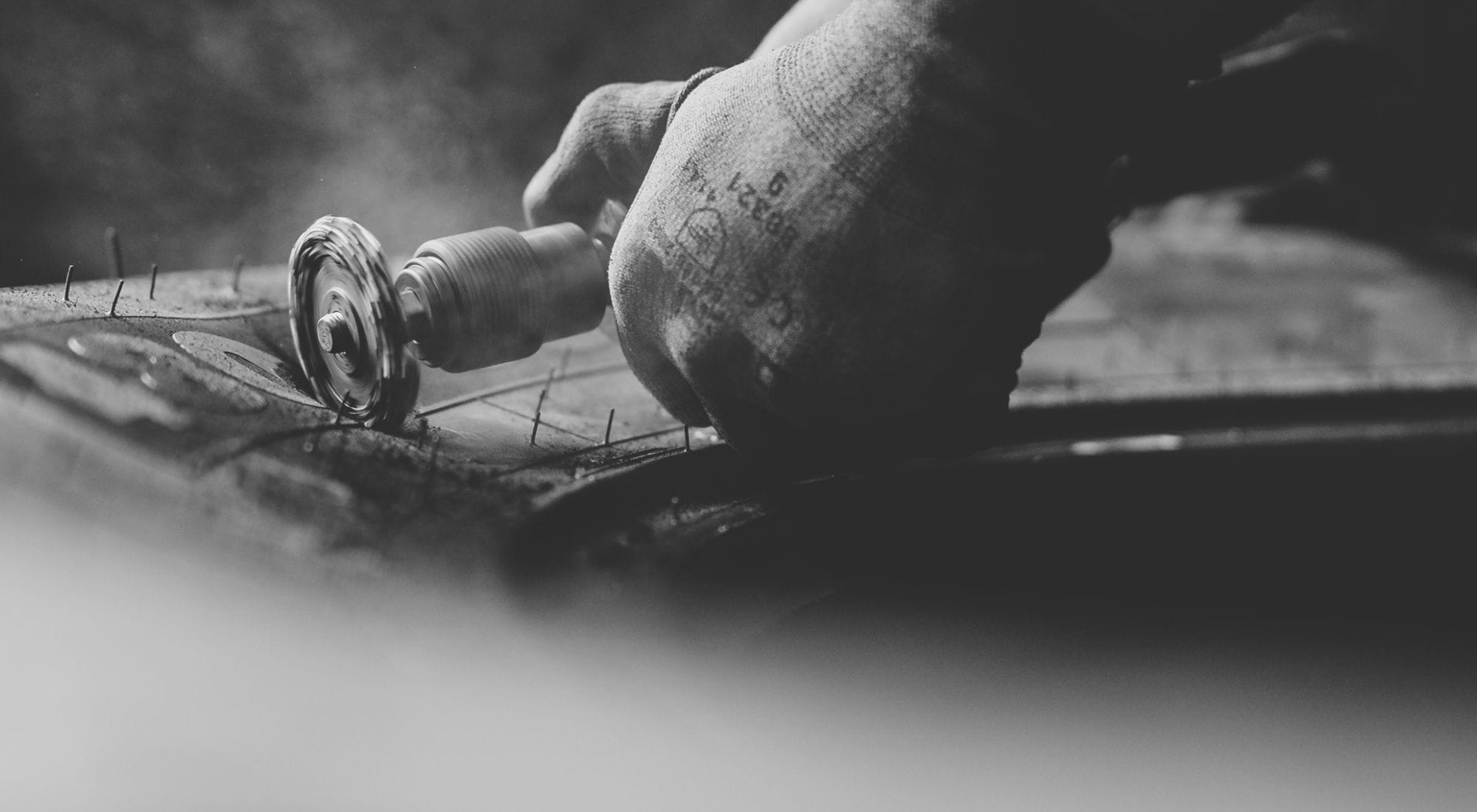 Nahaufnahme einer Hand mit Werkzeug bei der Reparatur eines großen Reifens.