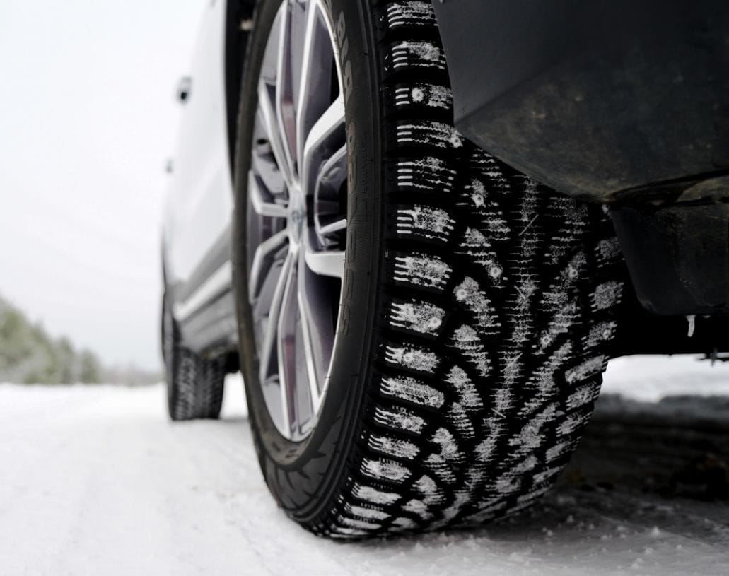 Nahaufnahme eines Winterreifens mit markantem Lamellenprofil auf Asphalt.