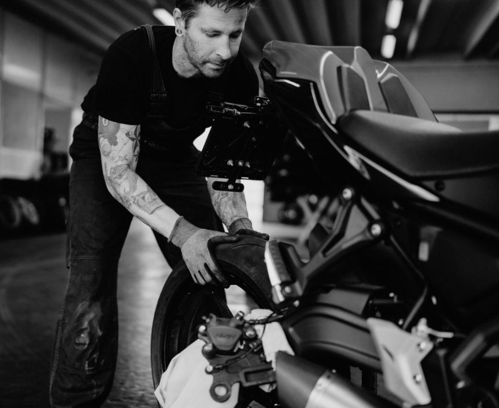 Mitarbeiter von Plankenauer arbeitet konzentriert am Hinterreifen eines Motorrads – beide Hände greifen zur präzisen Justierung an.