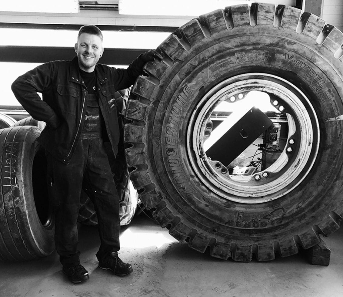 Mitarbeiter von Plankenauer steht neben einem großen Lkw-Reifen in der Werkstatt