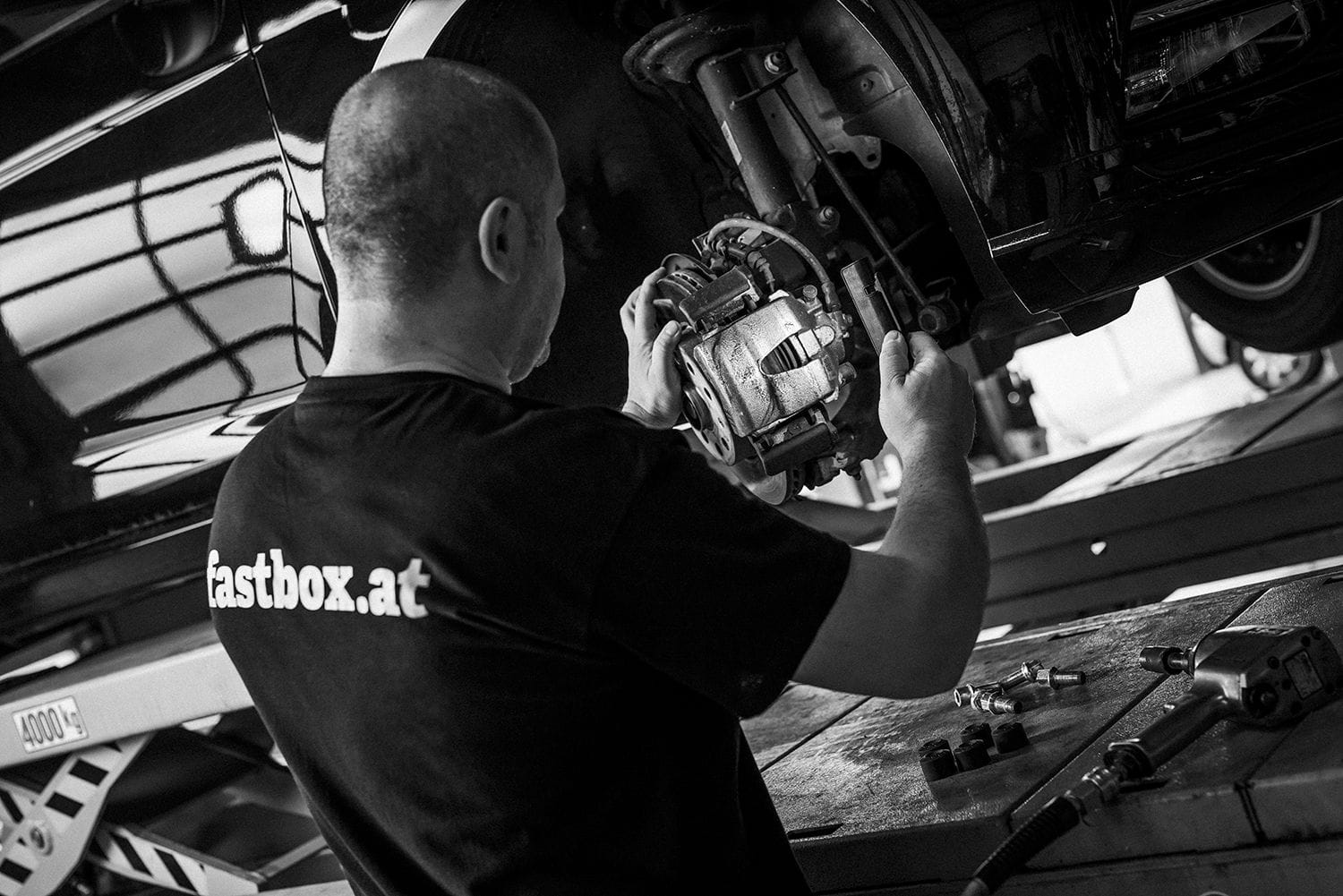 Ein Mechaniker arbeitet in einer modernen Schnellservice-Box an einem Fahrzeug.