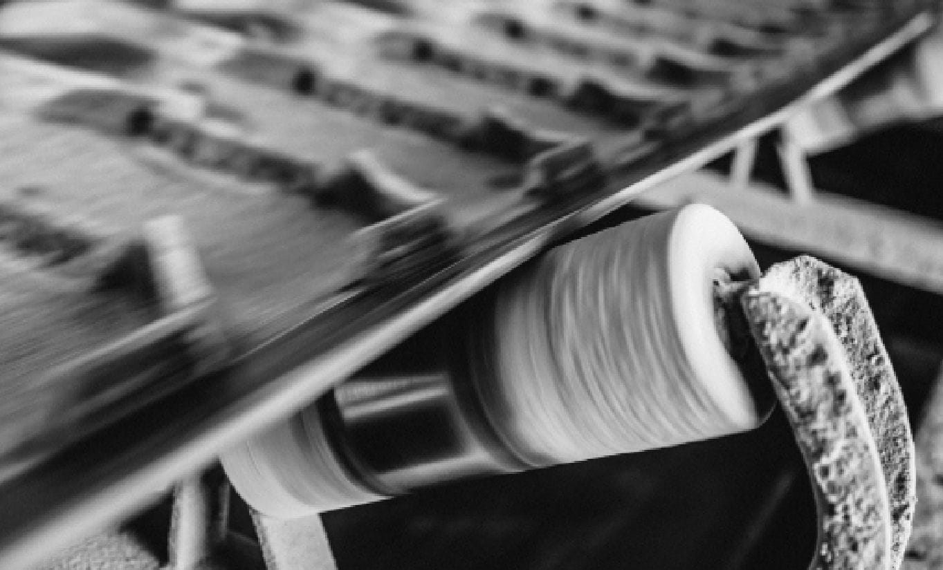 Nahaufnahme eines Gummiförderbandes mit sichtbaren Verbindungselementen und Rollen.