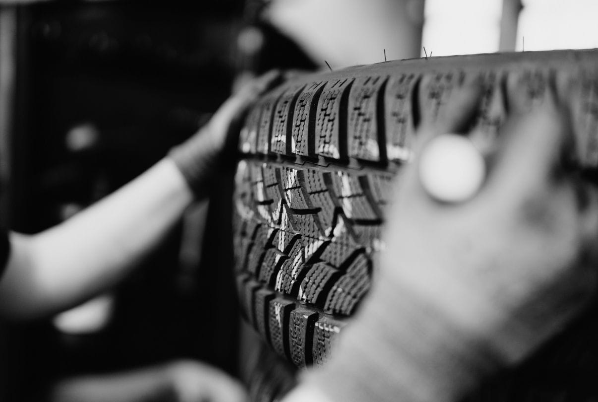 Nahaufnahme eines Reifens, der von zwei Händen gehalten wird.
